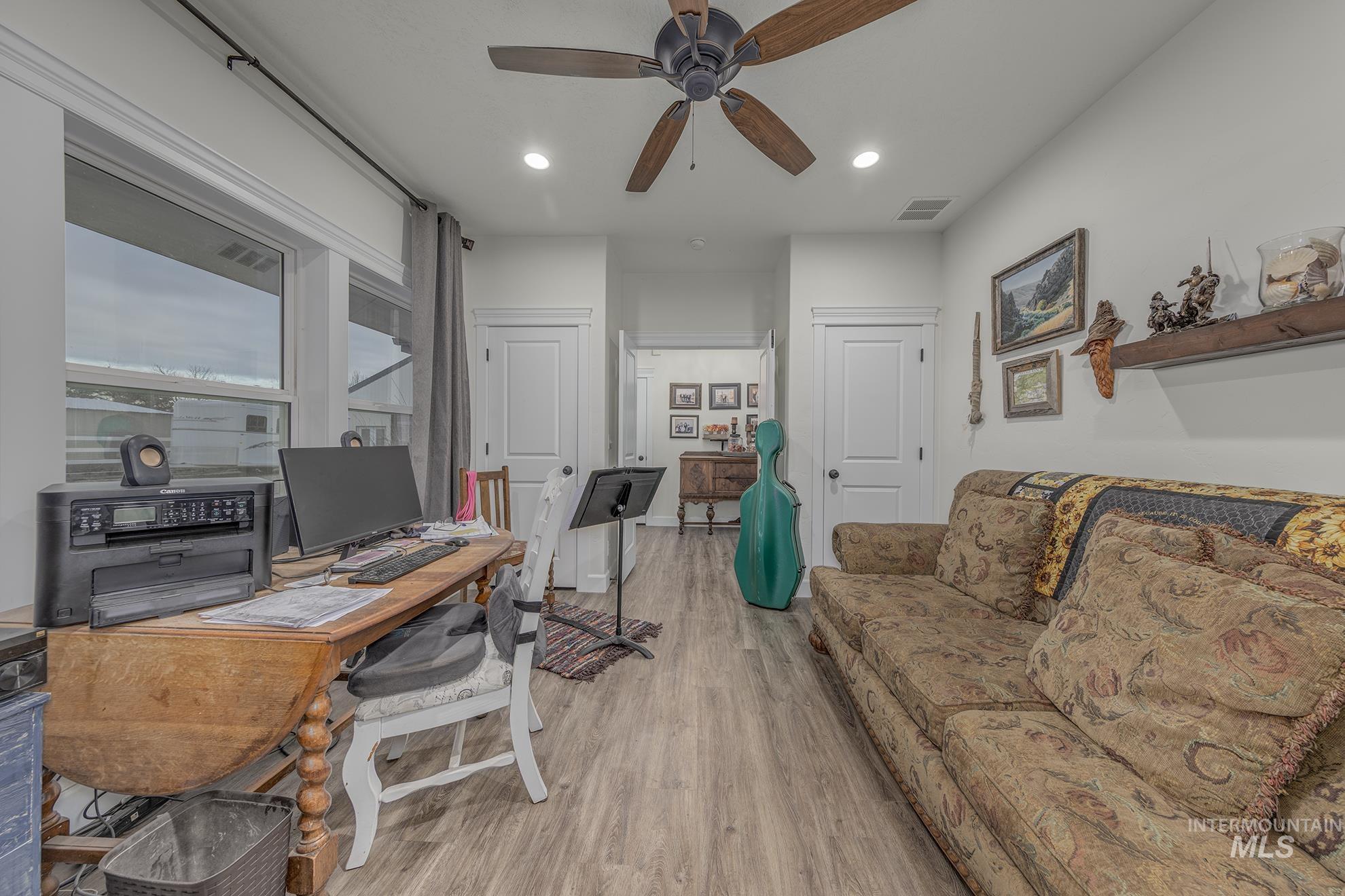 Office space featuring light wood finished floors, ceiling fan, and recessed lighting
