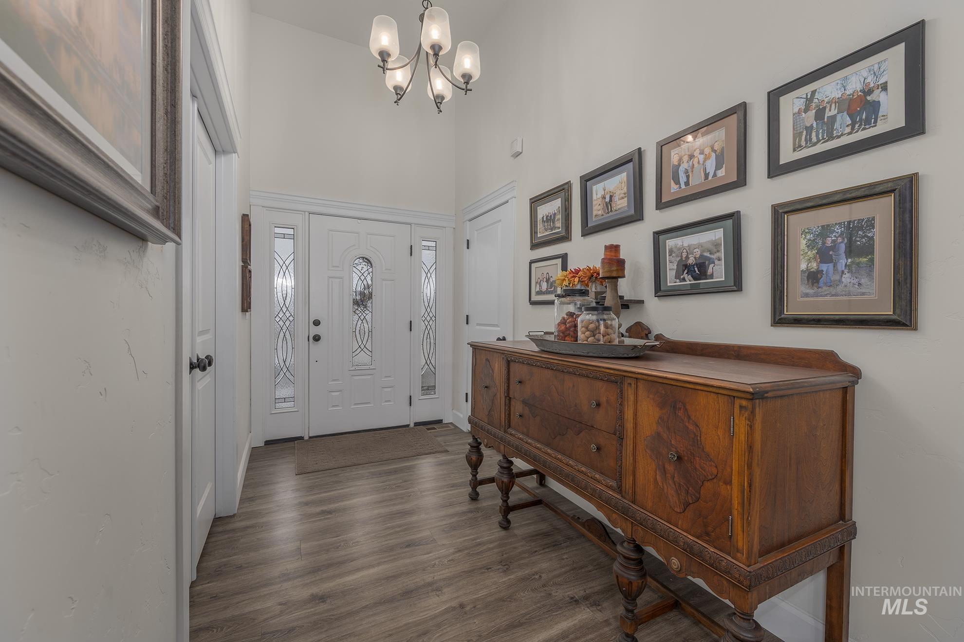 Foyer entrance featuring dark wood-style flooring, a chandelier, and a towering ceiling