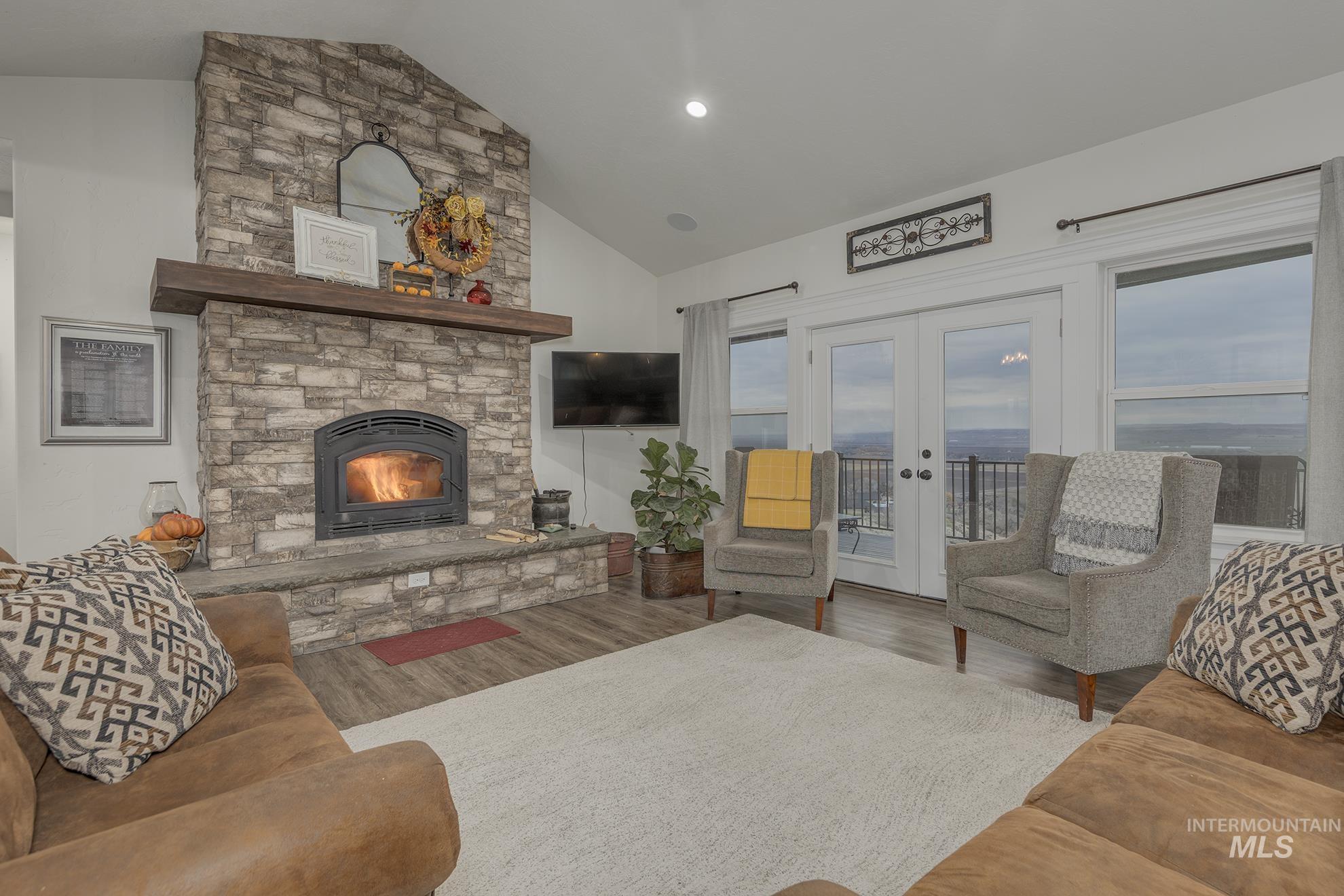 Living area with vaulted ceiling, a fireplace, french doors, wood finished floors, and recessed lighting