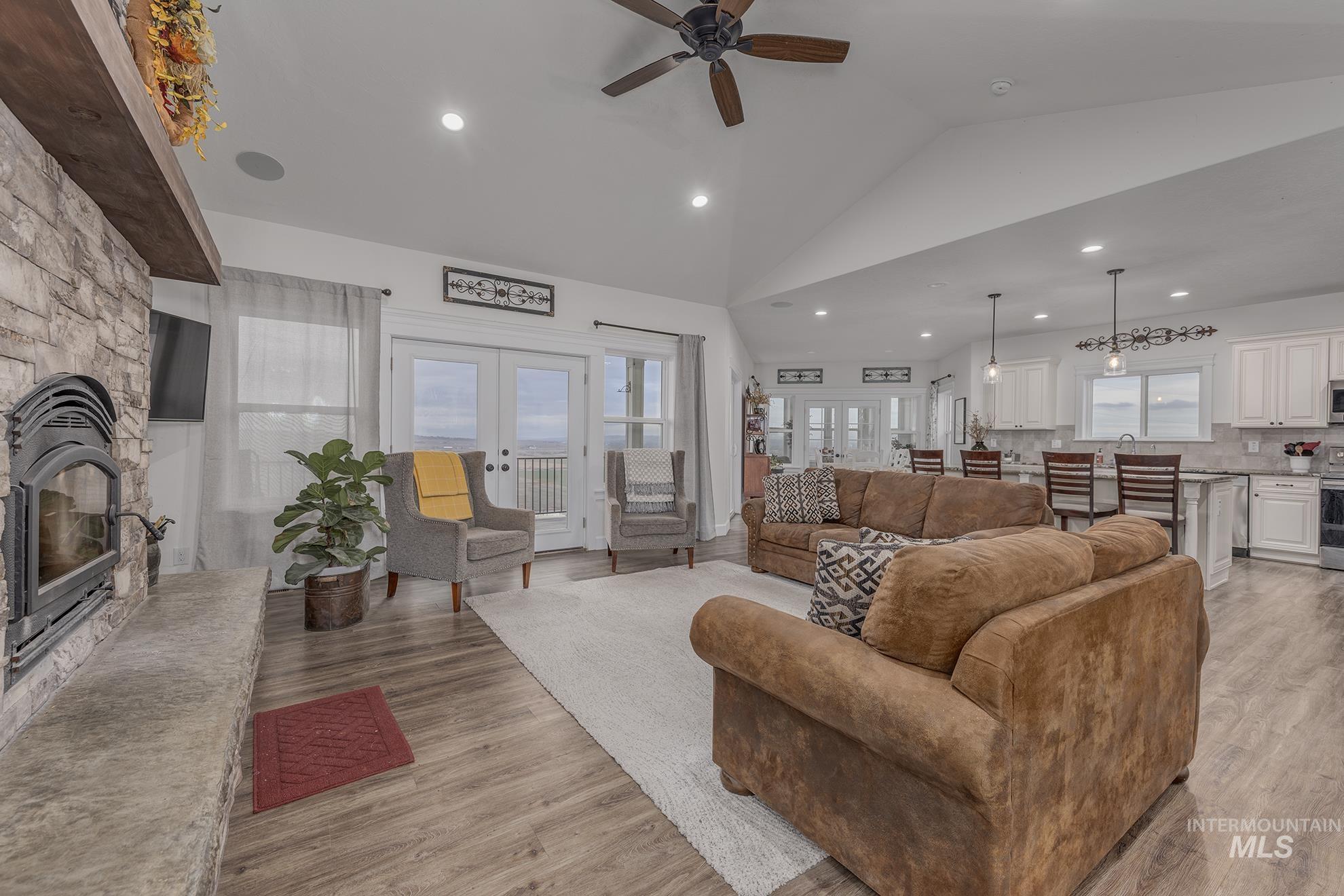 Living room with a fireplace, french doors, lofted ceiling, light wood-type flooring, and recessed lighting