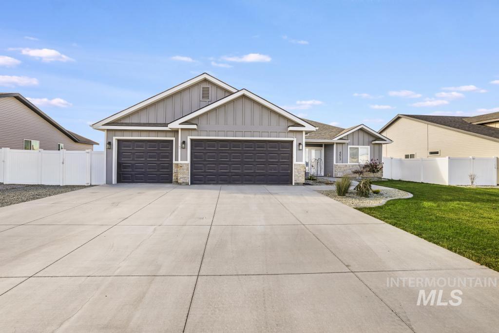 View of front of home featuring board and batten siding, stone siding, driveway, and a garage