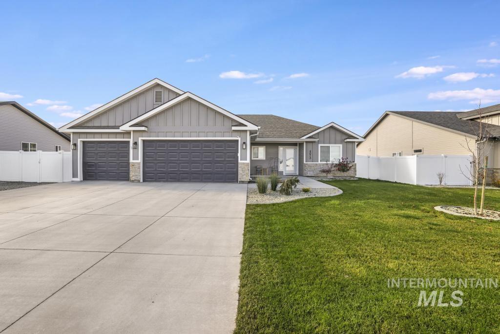 View of front of home featuring board and batten siding, an attached garage, concrete driveway, and stone siding