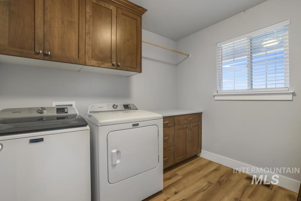Washroom featuring cabinet space, independent washer and dryer, and light wood finished floors