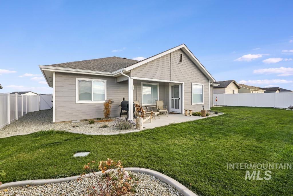 Rear view of property with a fenced backyard, a patio area, and roof with shingles