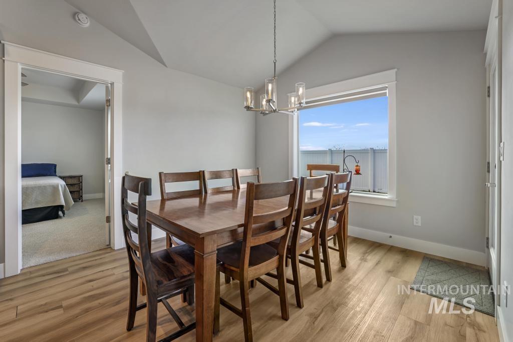 Dining space with vaulted ceiling, light wood finished floors, and a chandelier