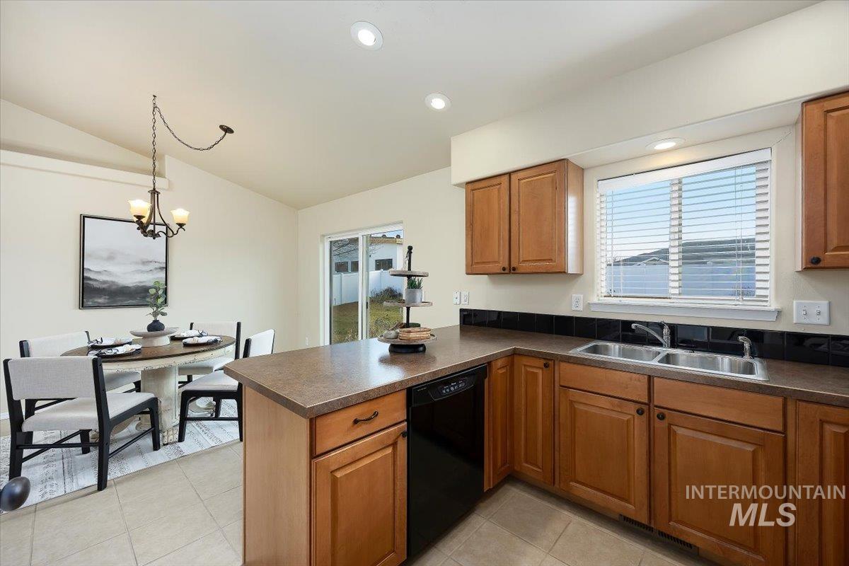 Kitchen featuring dark countertops, brown cabinets, a peninsula, dishwasher, and recessed lighting