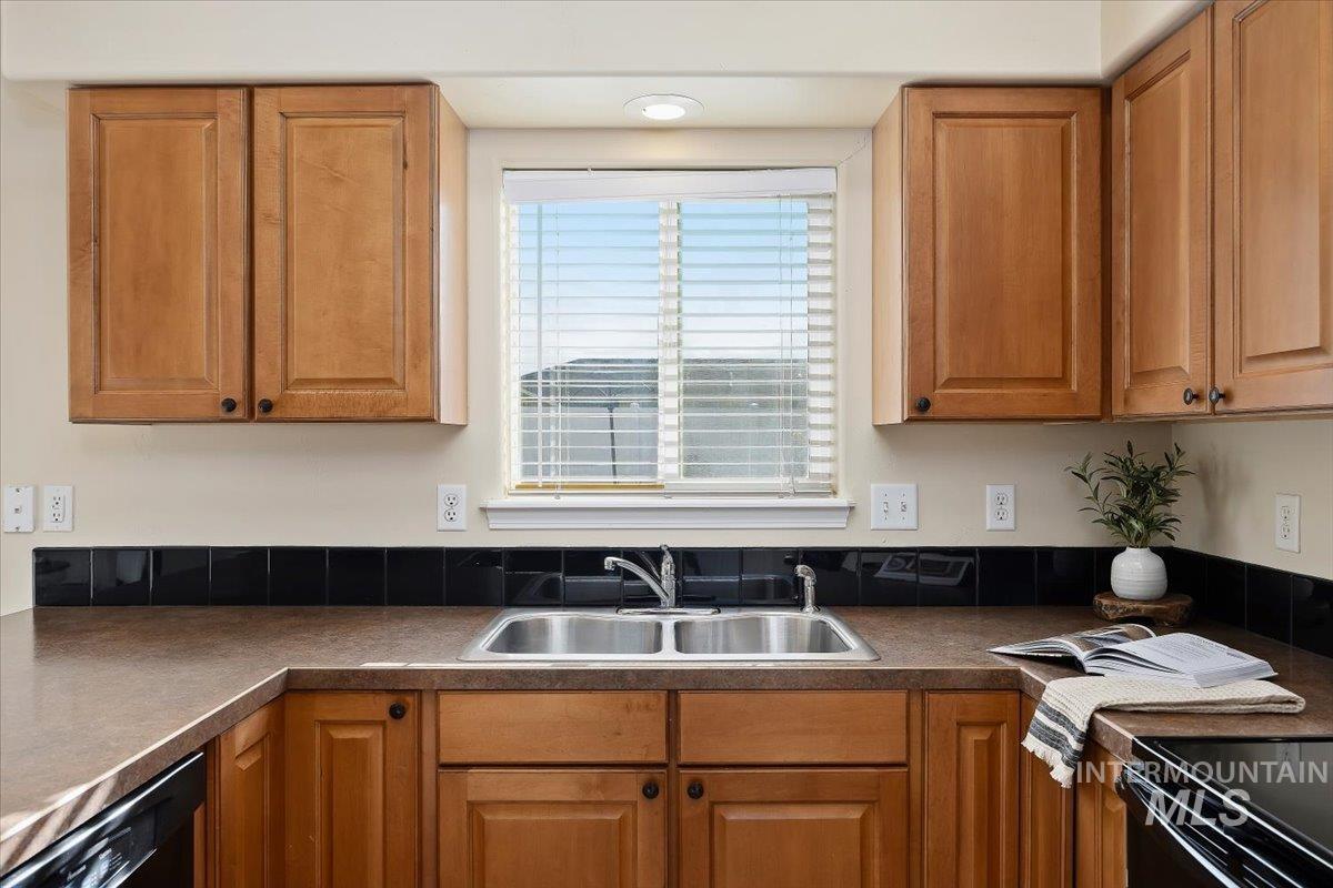 Kitchen with dark countertops, brown cabinets, and black appliances