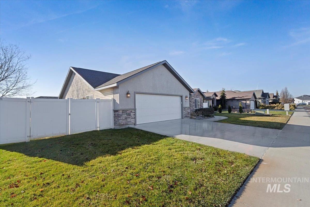 View of side of property featuring concrete driveway, stone siding, and an attached garage