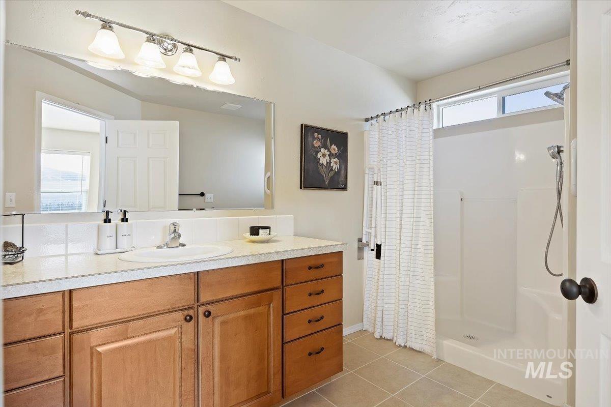 Full bath featuring a shower with curtain, light tile patterned floors, and vanity