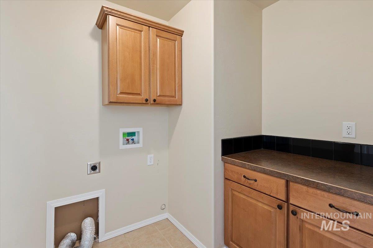 Laundry room featuring cabinet space, hookup for an electric dryer, hookup for a washing machine, and light tile patterned flooring