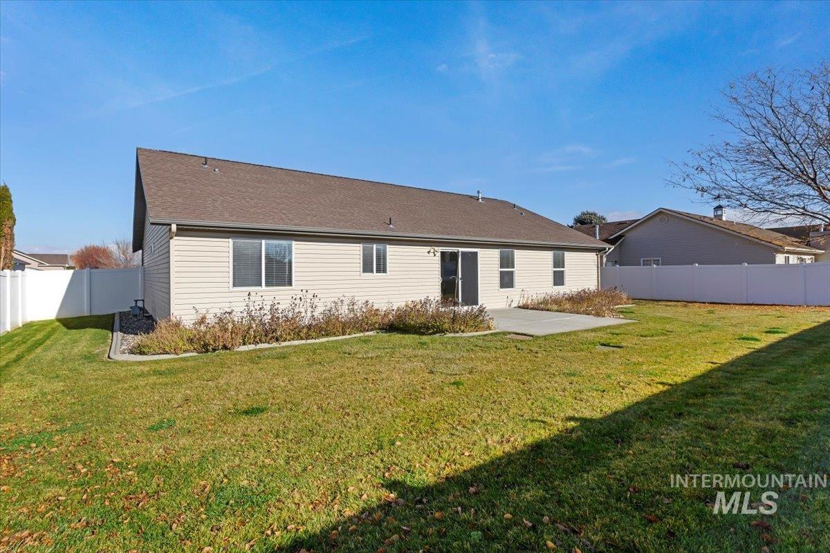 Back of house featuring a fenced backyard, a patio area, and a shingled roof