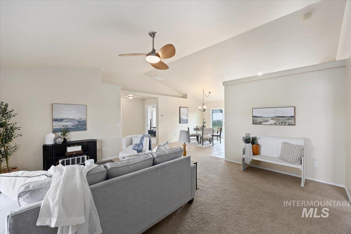 Living room with ceiling fan, carpet, a chandelier, and high vaulted ceiling