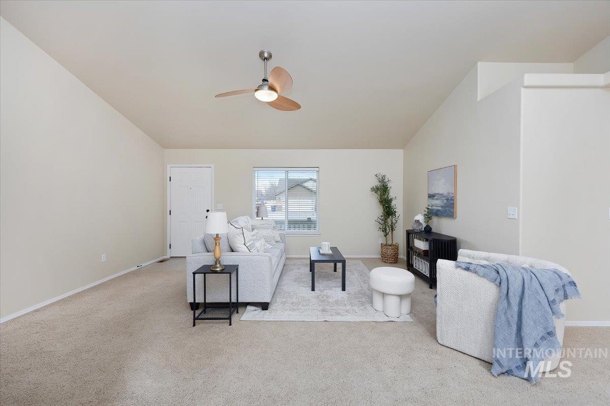 Living area with light carpet, vaulted ceiling, and ceiling fan