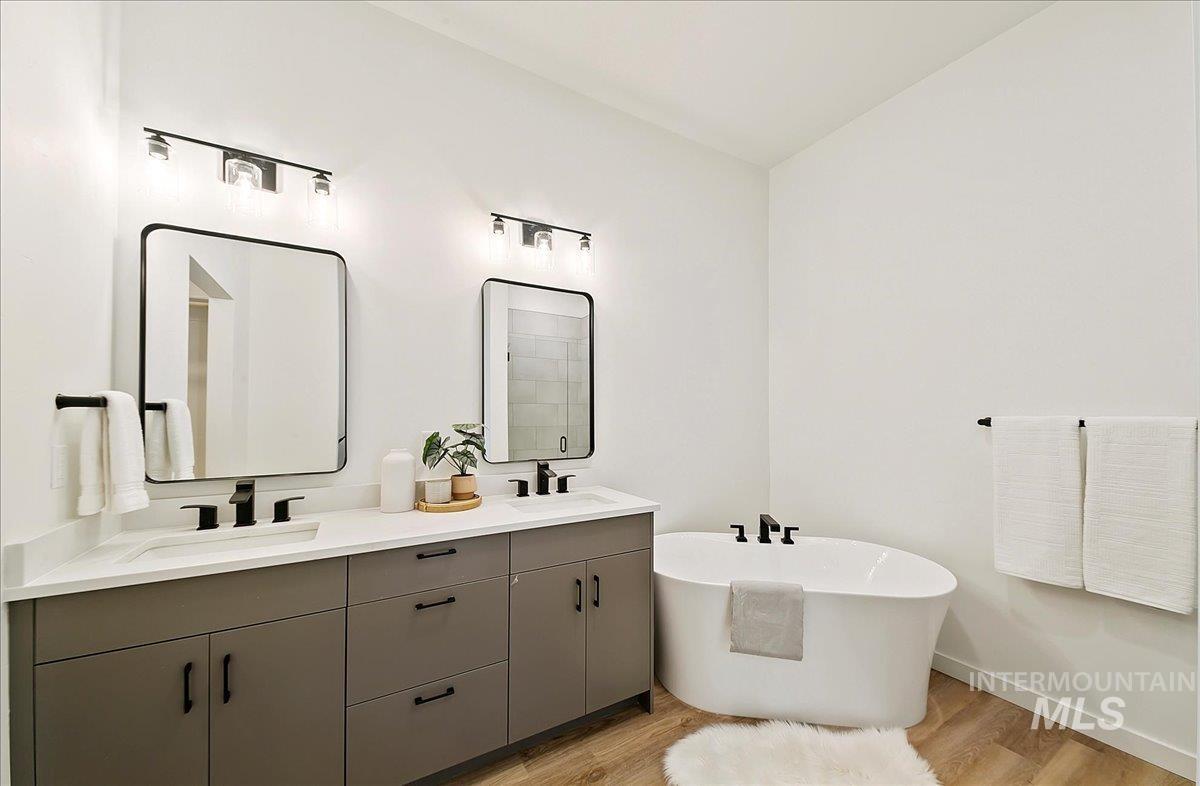 Full bath with double vanity, wood finished floors, and a freestanding tub