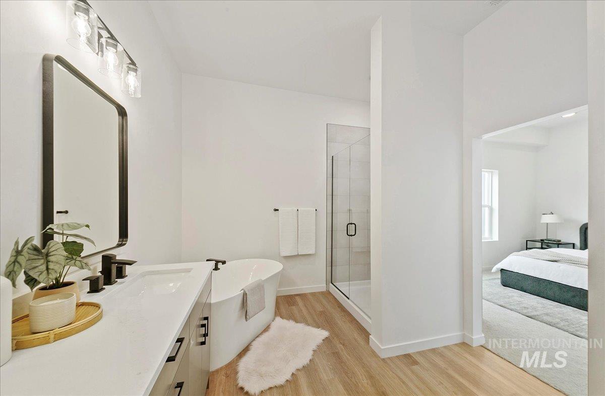 Full bath with wood finished floors, a stall shower, vanity, a soaking tub, and ensuite bathroom