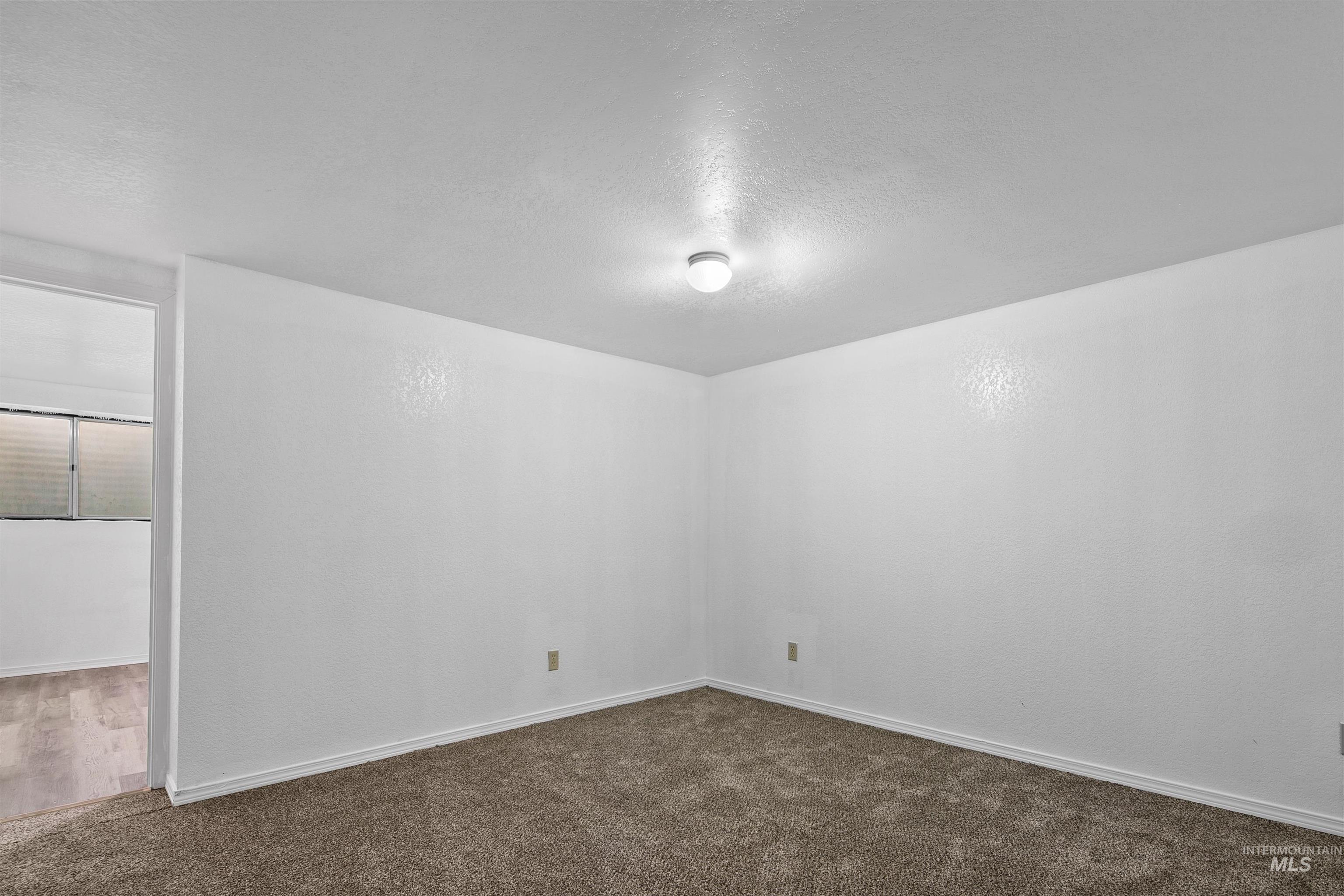 Unfurnished room featuring a textured ceiling and dark colored carpet