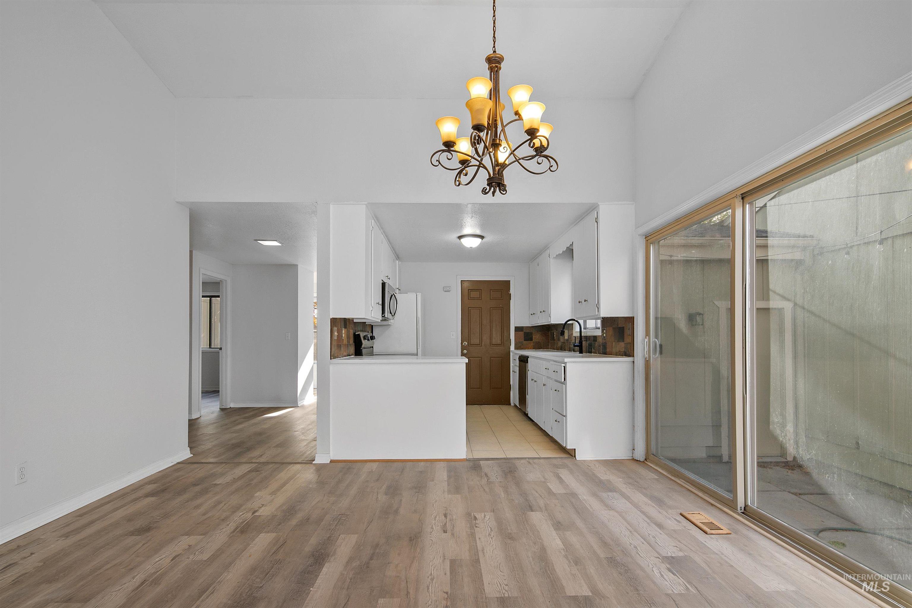 Kitchen with white cabinetry, light countertops, light wood-type flooring, decorative light fixtures, and a chandelier