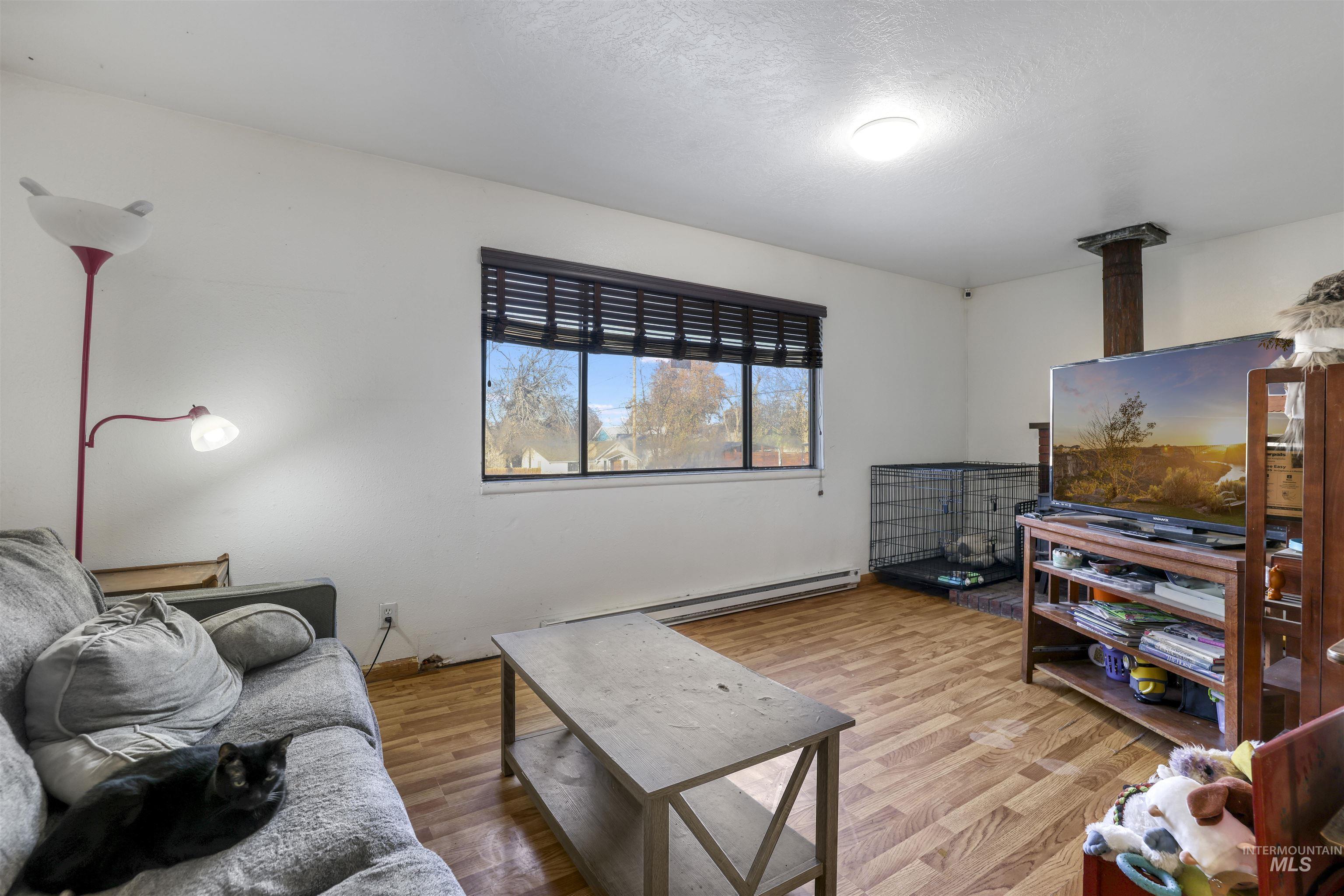 Living room featuring baseboard heating, wood finished floors, and a textured ceiling