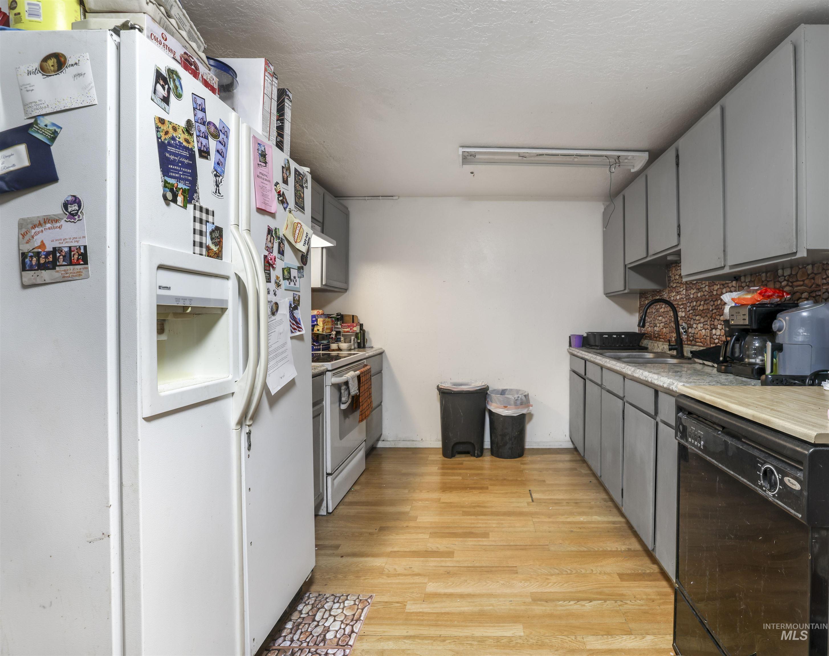 Kitchen with white appliances, gray cabinets, light wood-style floors, light countertops, and a textured ceiling