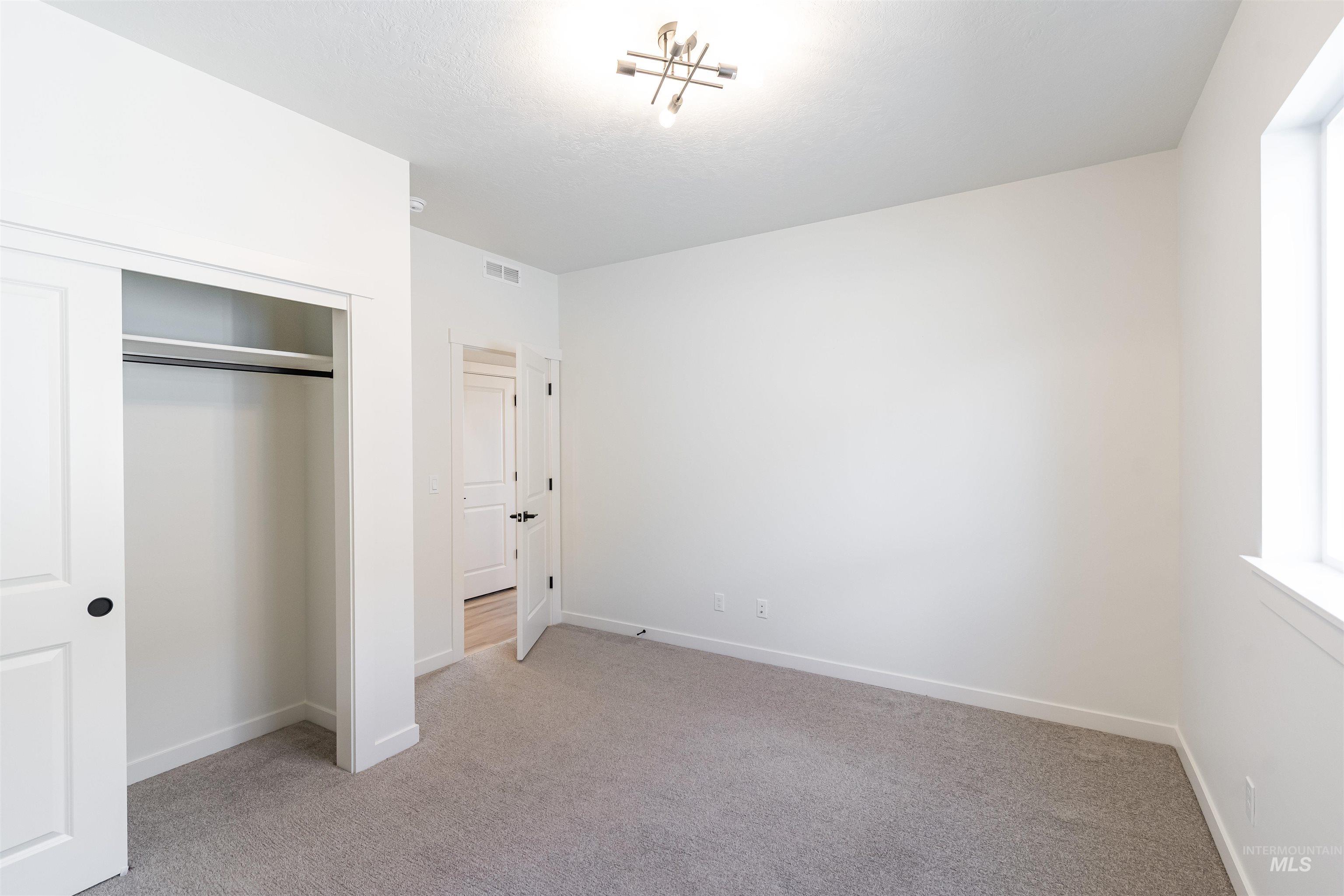 Unfurnished bedroom with light colored carpet and a closet