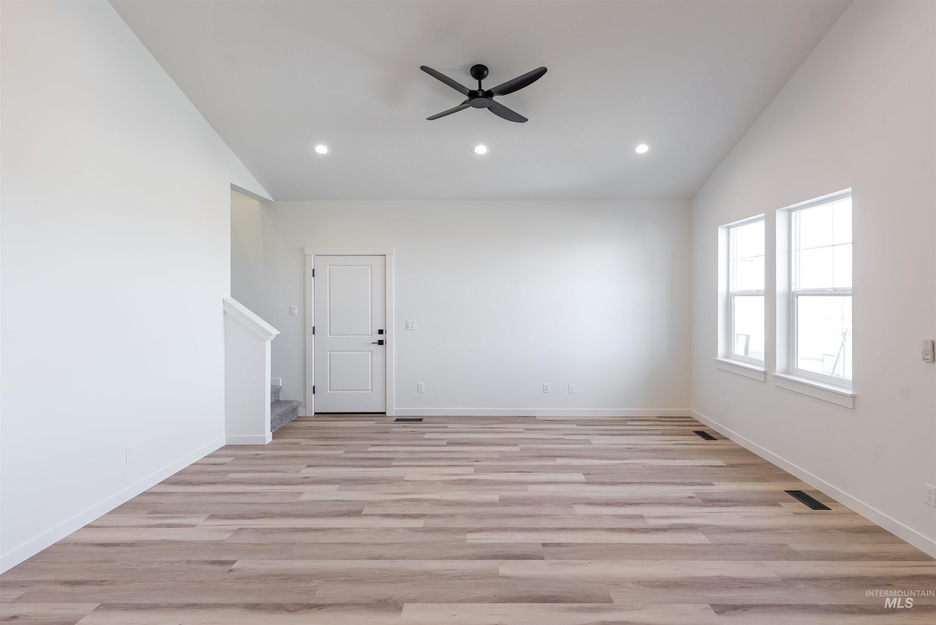 Spare room with lofted ceiling, light wood-style floors, stairs, ceiling fan, and recessed lighting