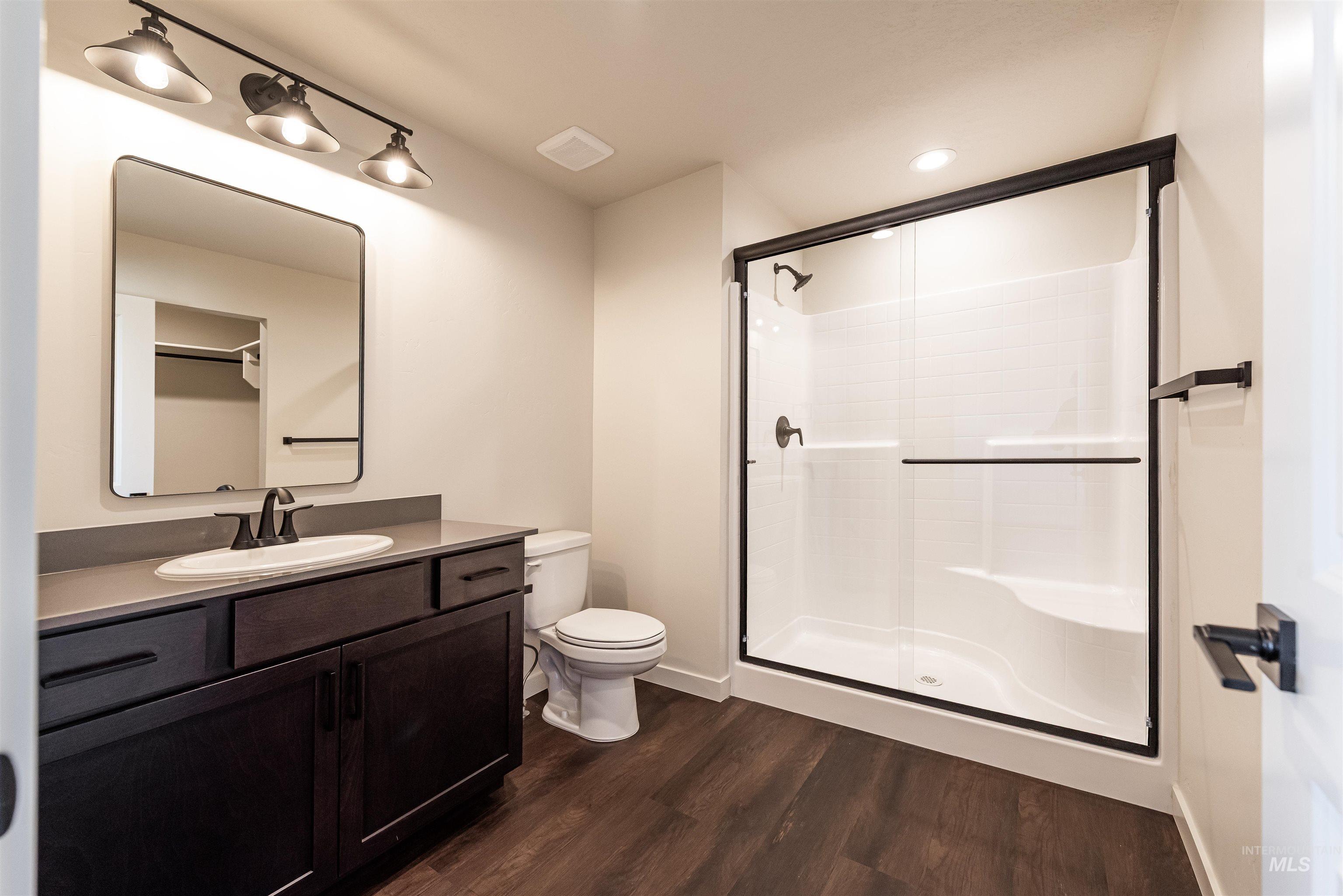 Bathroom with vanity, a shower stall, dark wood-type flooring, and recessed lighting