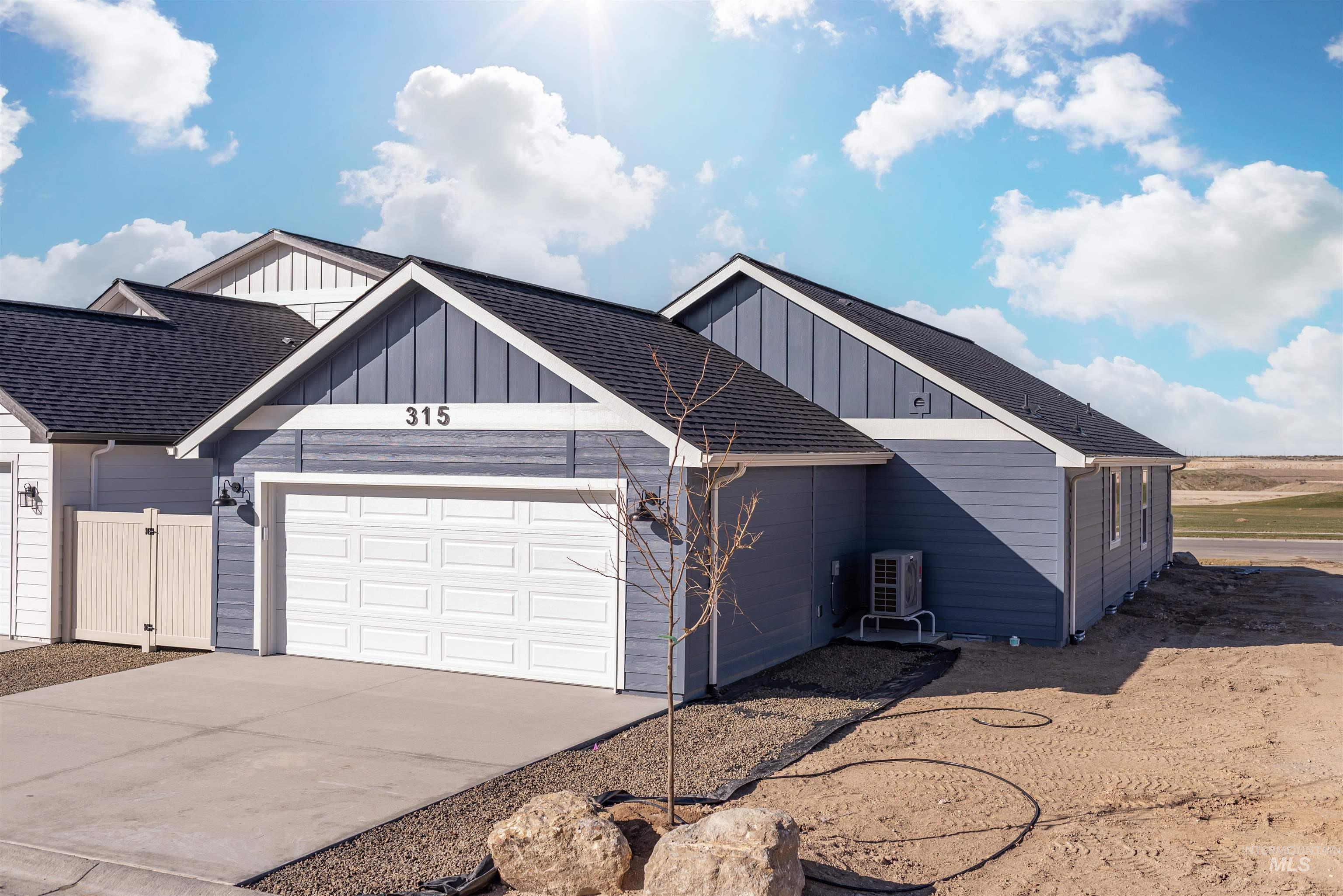 View of front facade with board and batten siding, roof with shingles, concrete driveway, and a garage