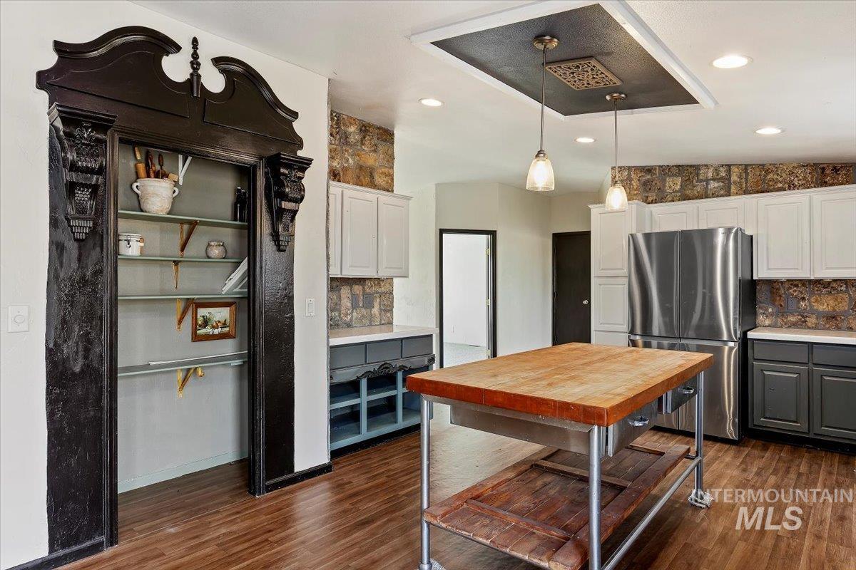 Kitchen featuring white cabinetry, gray cabinetry, freestanding refrigerator, hanging light fixtures, and recessed lighting