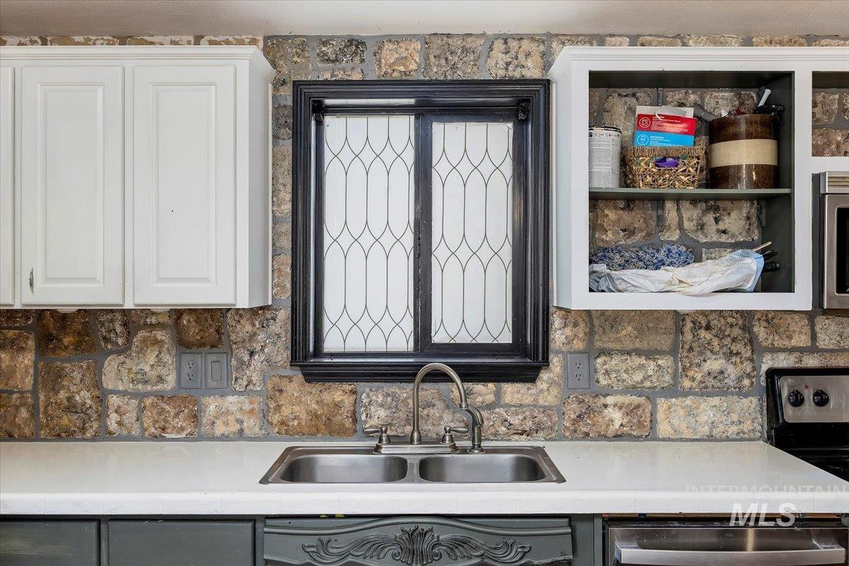 Kitchen with white cabinetry, appliances with stainless steel finishes, and tasteful backsplash