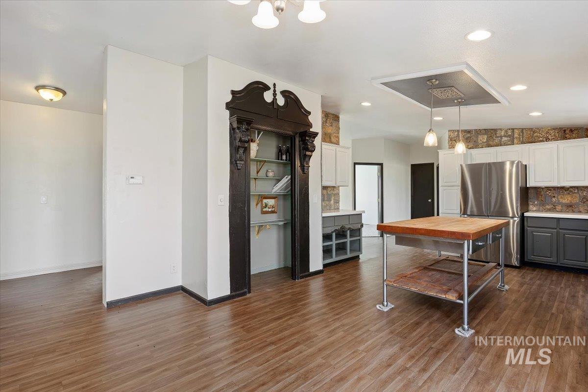 Kitchen with backsplash, freestanding refrigerator, hanging light fixtures, gray cabinets, and lofted ceiling