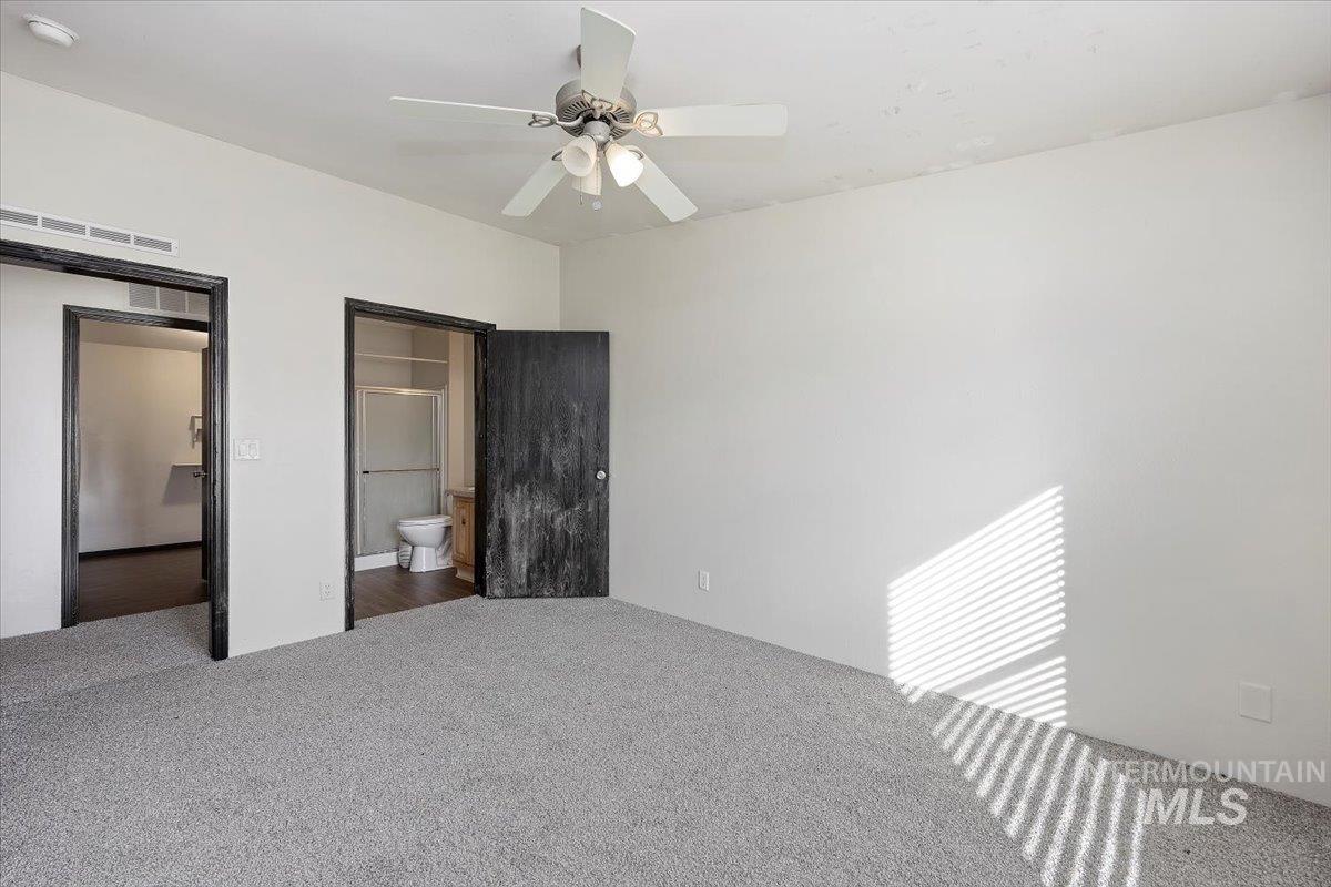 Unfurnished bedroom with carpet flooring, a ceiling fan, and ensuite bath