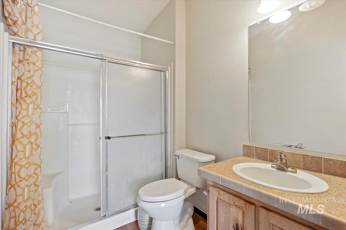 Full bathroom featuring a stall shower, vanity, and a textured wall