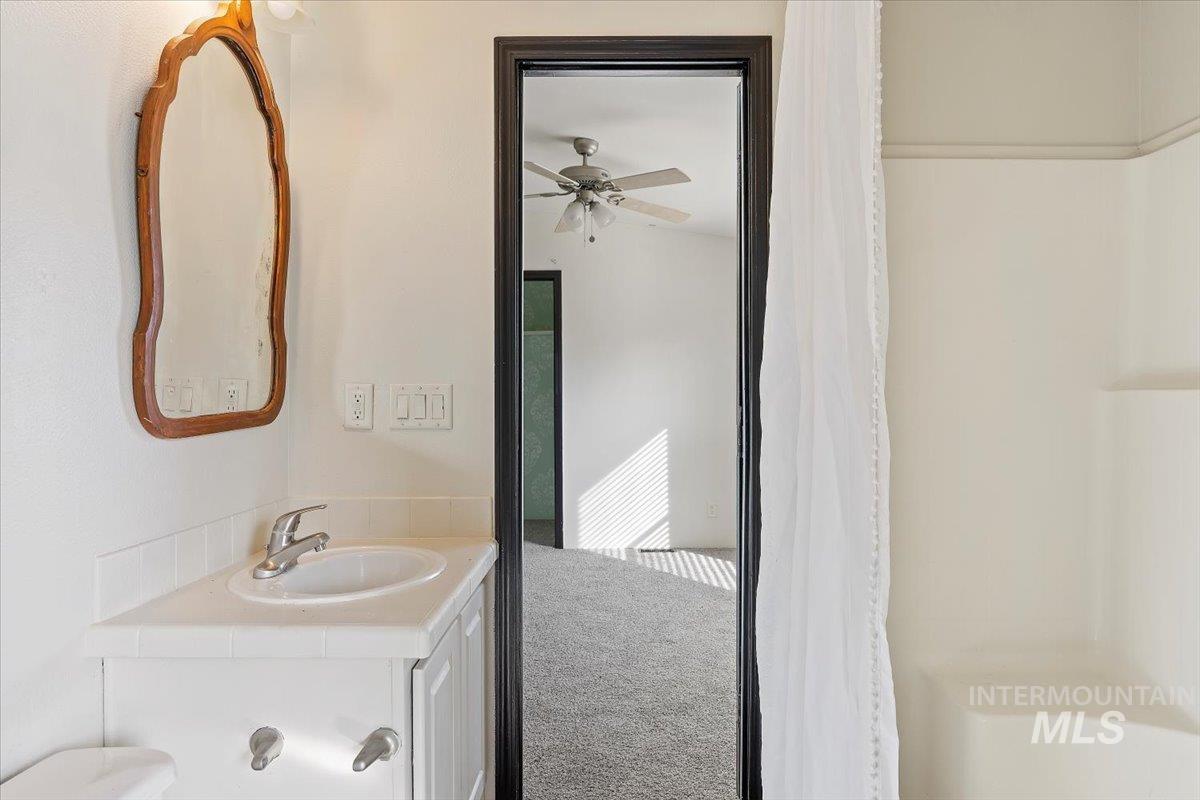 Full bath featuring carpet flooring, curtained shower, vanity, and ceiling fan