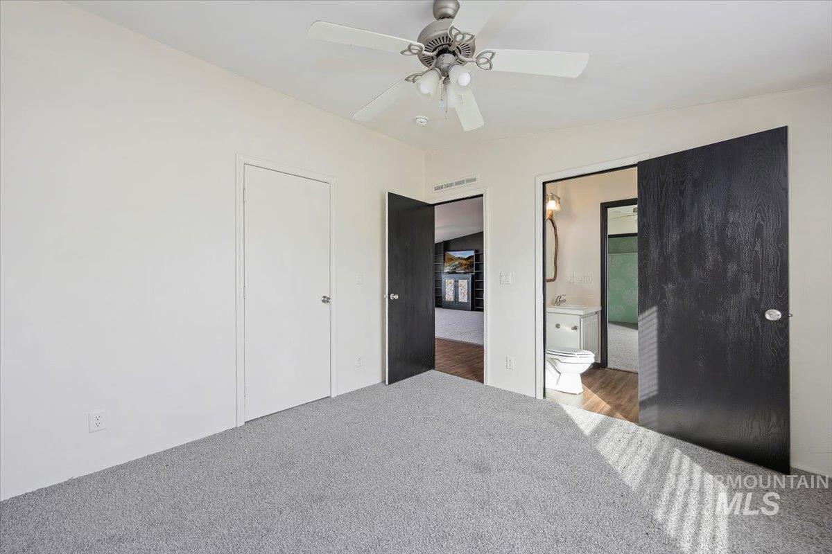 Bedroom with carpet floors, a ceiling fan, and connected bathroom