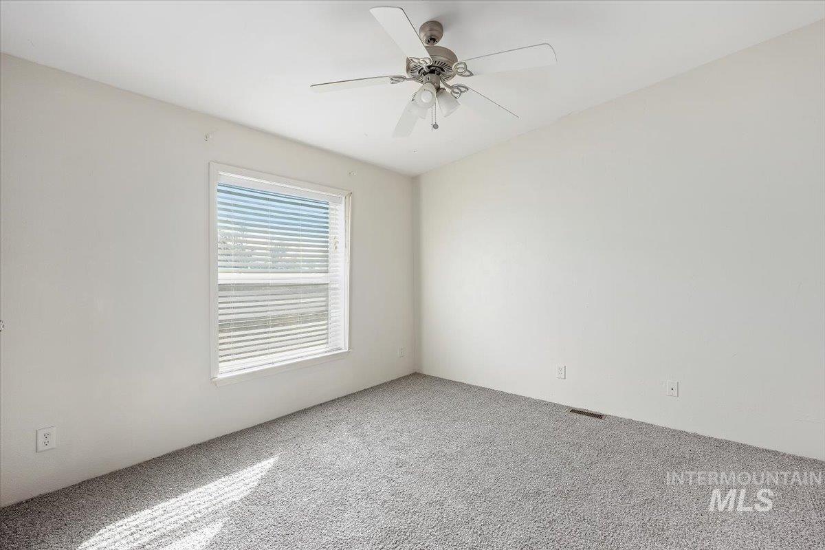 Carpeted spare room with a ceiling fan