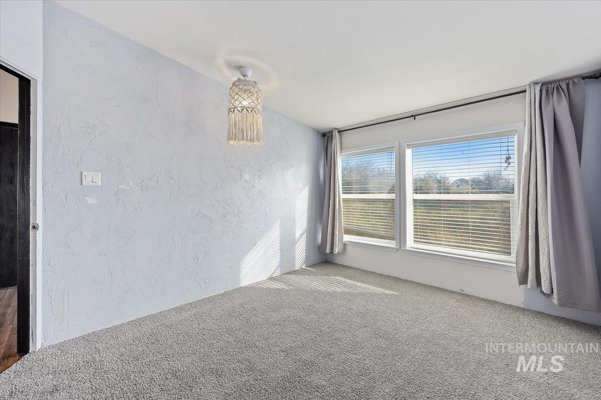 Carpeted spare room featuring a textured wall