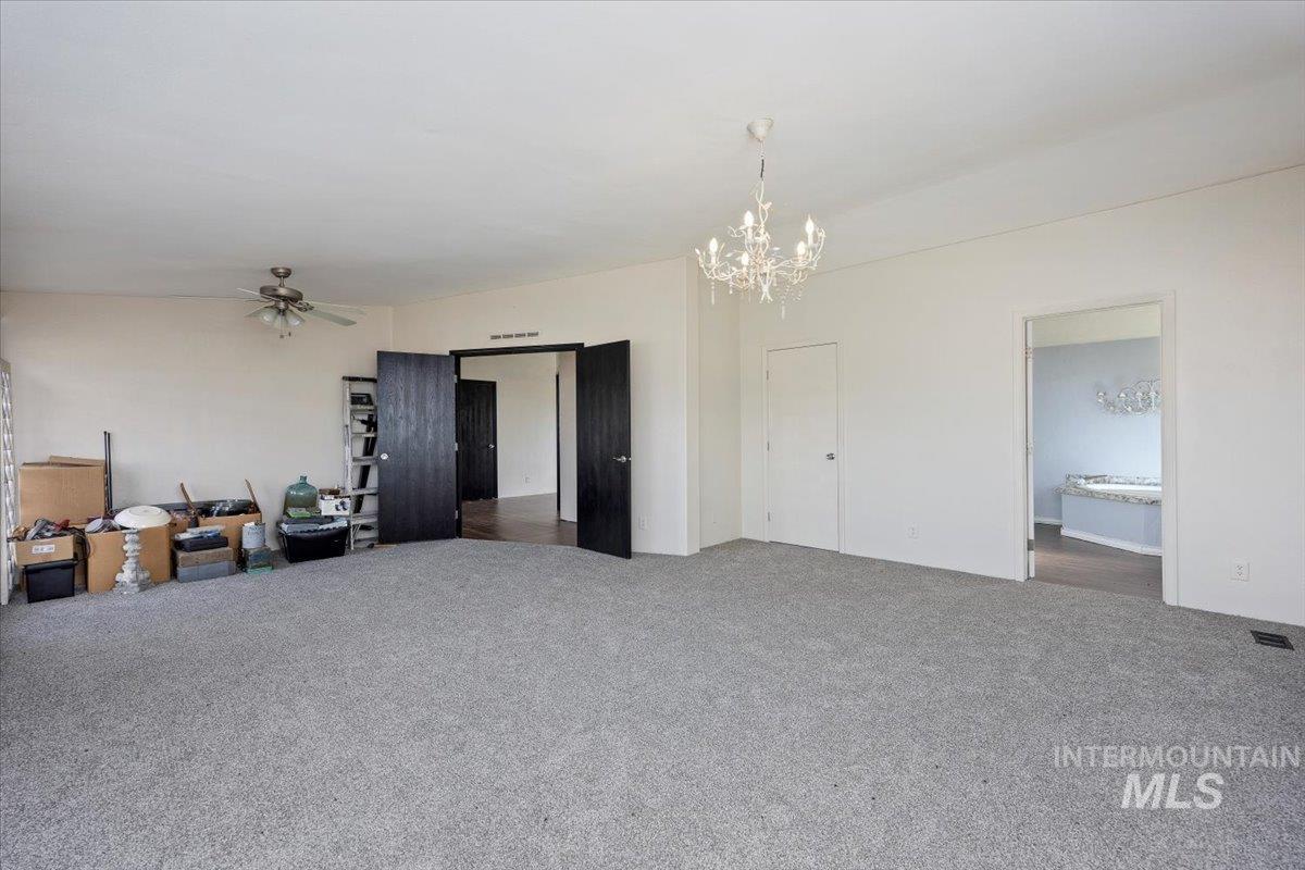 Spare room with carpet floors, a chandelier, and a ceiling fan