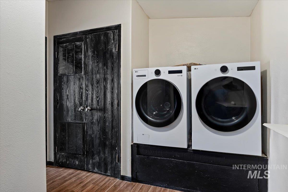 Washroom featuring wood finished floors, washing machine and clothes dryer, and a textured wall