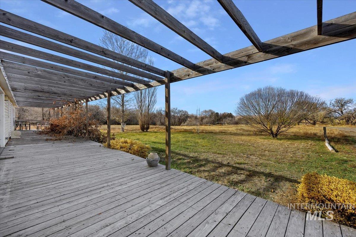 Wooden deck featuring a lawn and a pergola