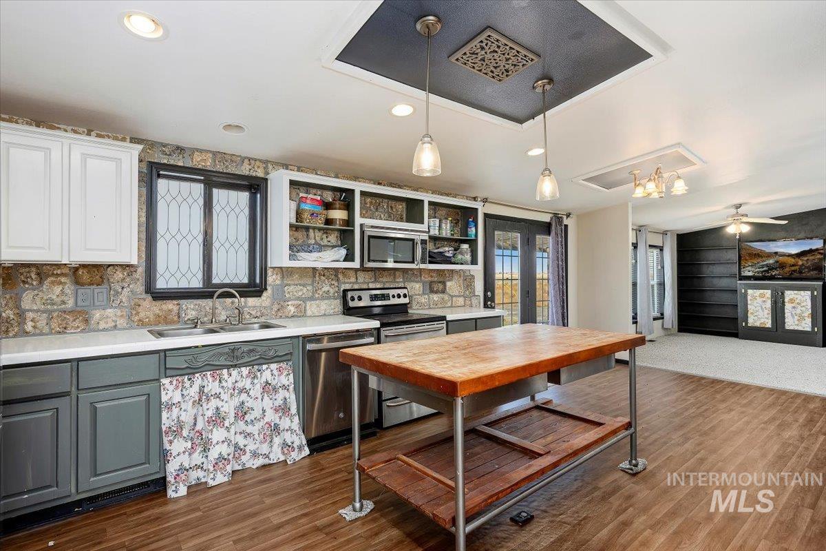 Kitchen with hanging light fixtures, stainless steel appliances, gray cabinetry, healthy amount of natural light, and recessed lighting