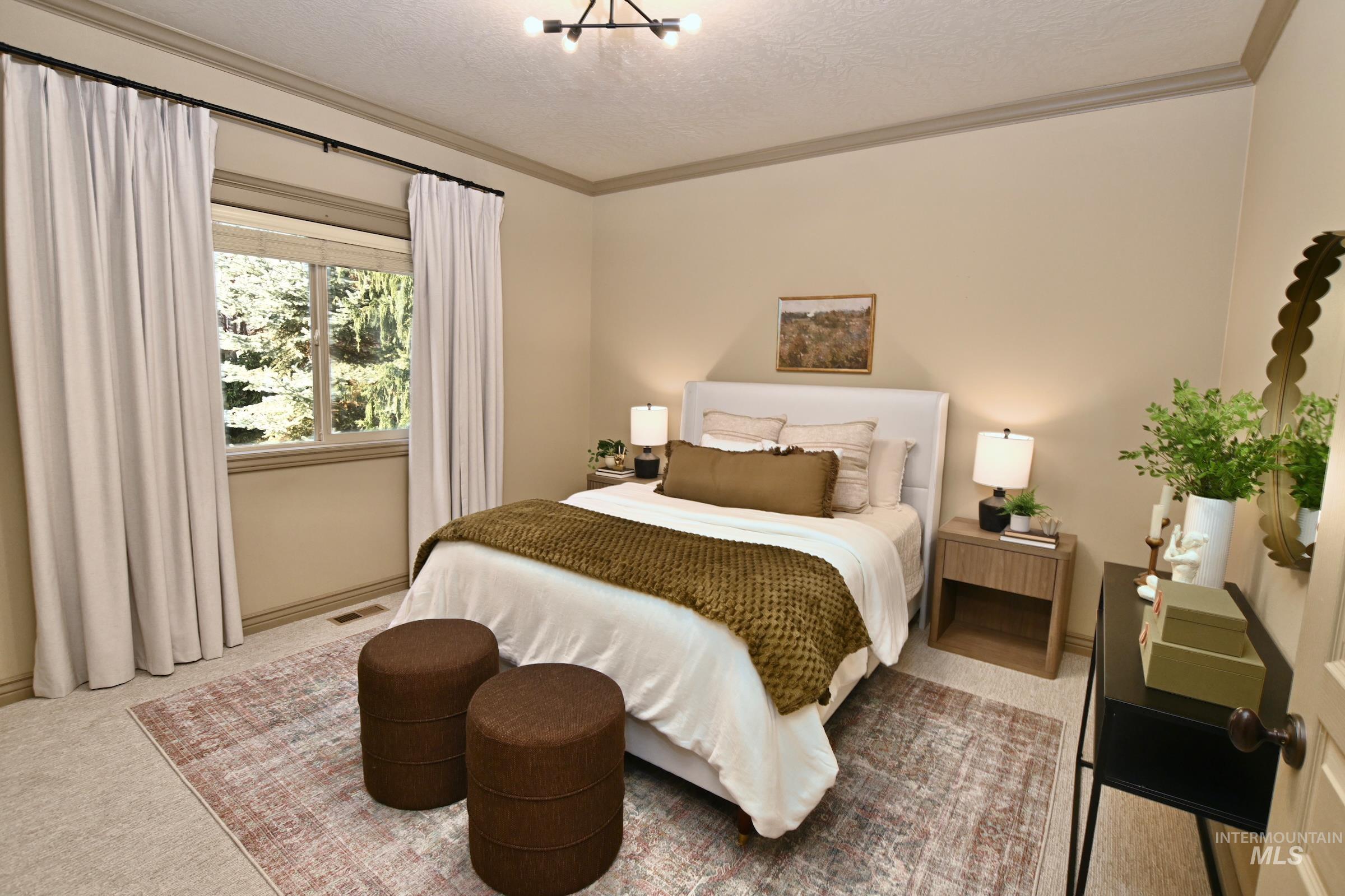 Carpeted bedroom featuring a textured ceiling, a chandelier, and crown molding