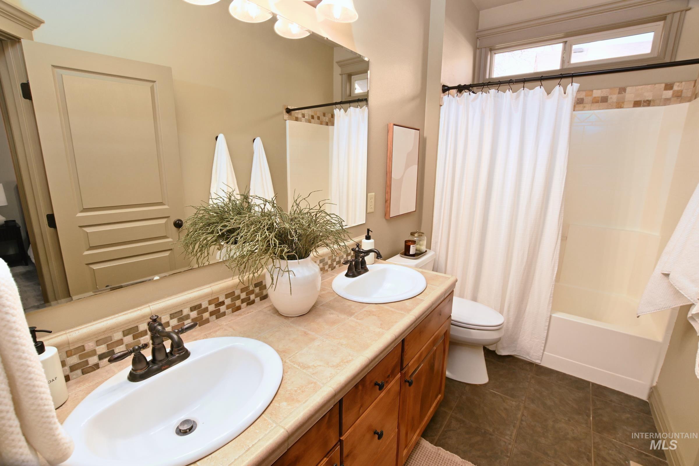 Bathroom with double vanity and shower / bath combination with curtain