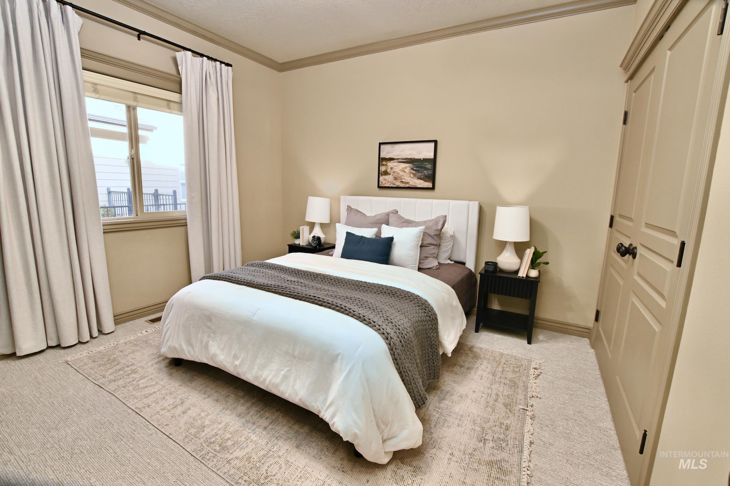 Carpeted bedroom with a closet and crown molding