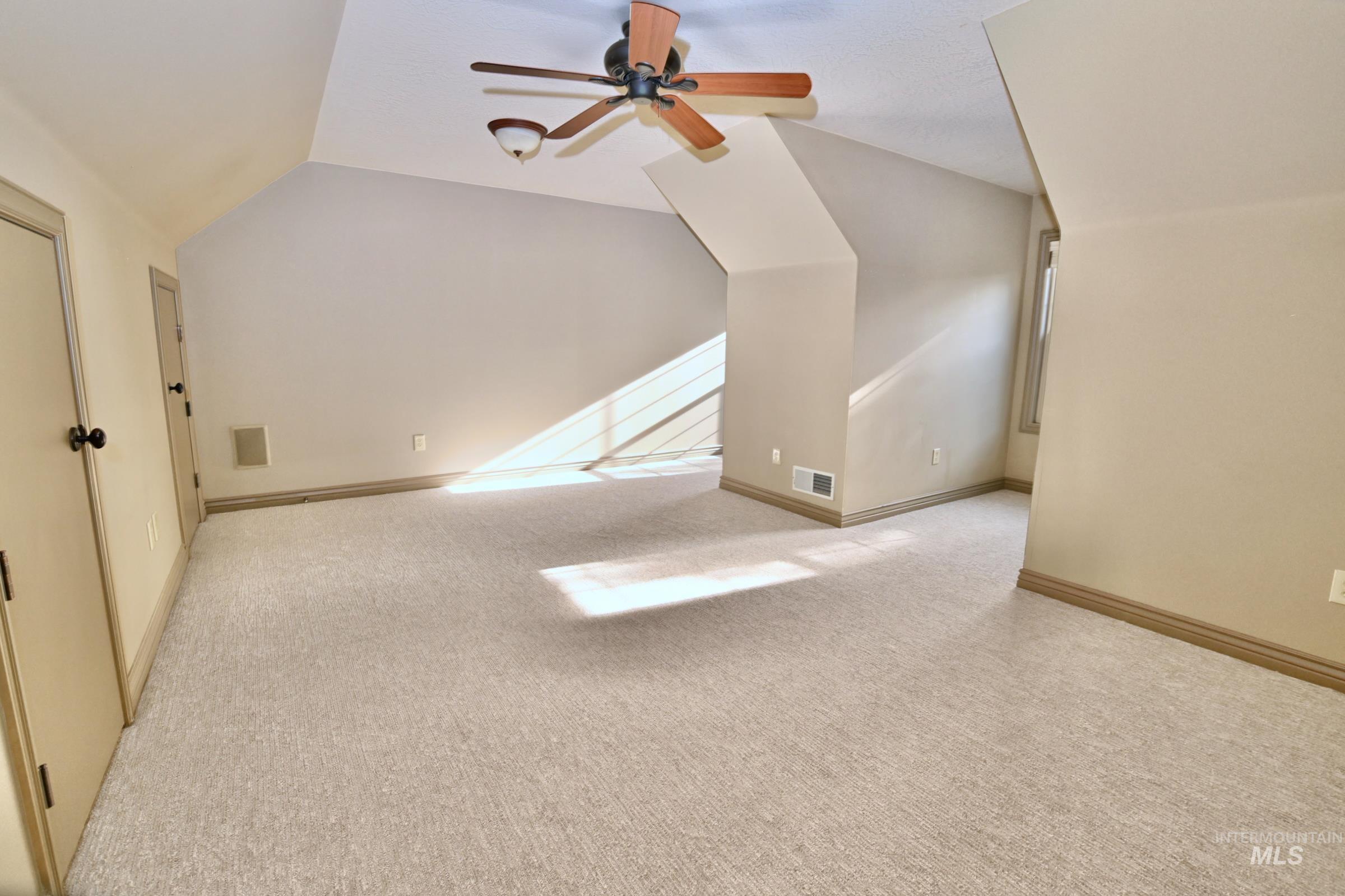 Bonus room featuring light colored carpet, vaulted ceiling, and a ceiling fan