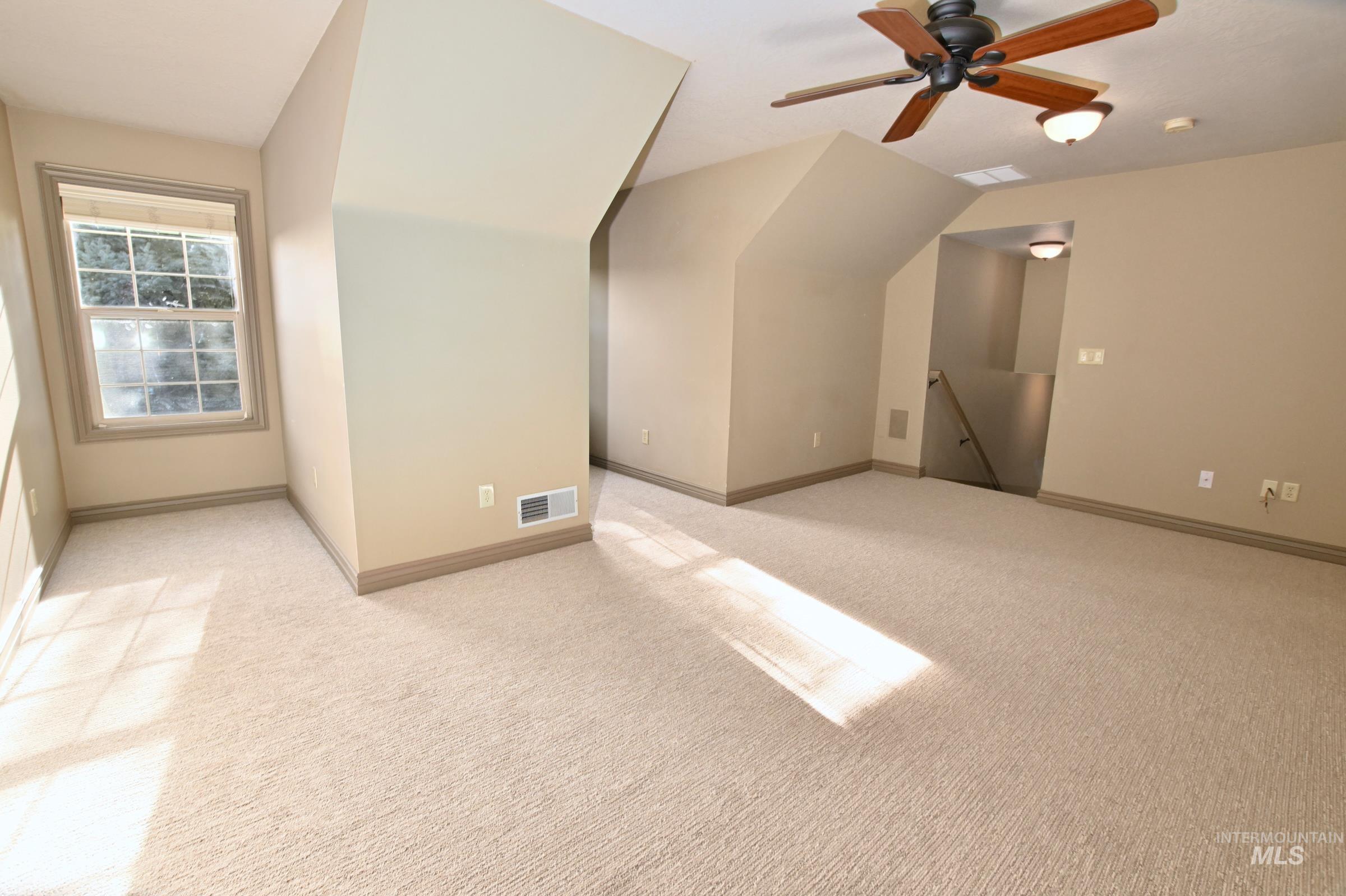 Bonus room with ceiling fan, light colored carpet, and vaulted ceiling