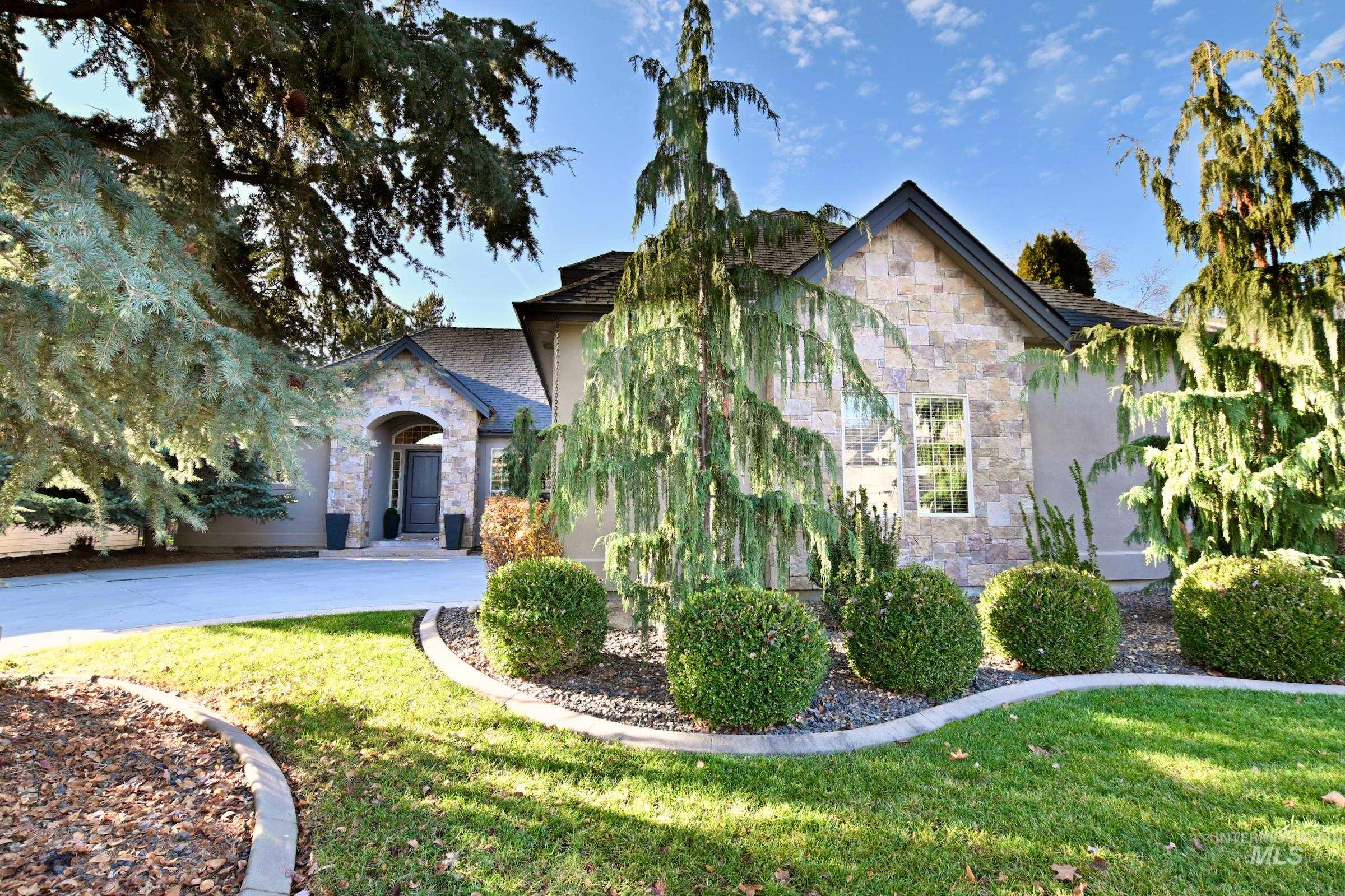 View of front facade featuring stone siding, a front yard, and stucco siding