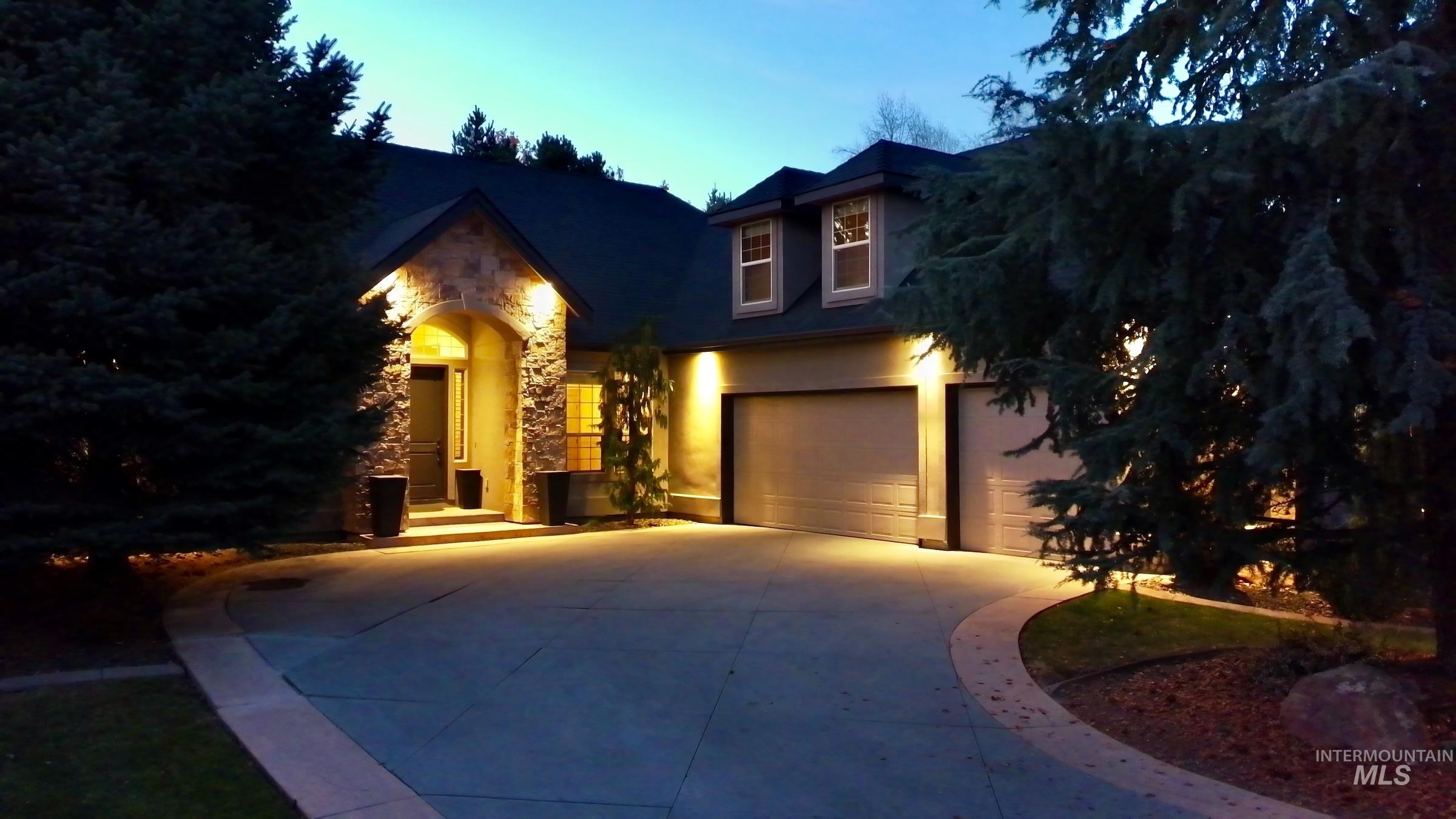 View of front facade with stone siding, driveway, stucco siding, and an attached garage