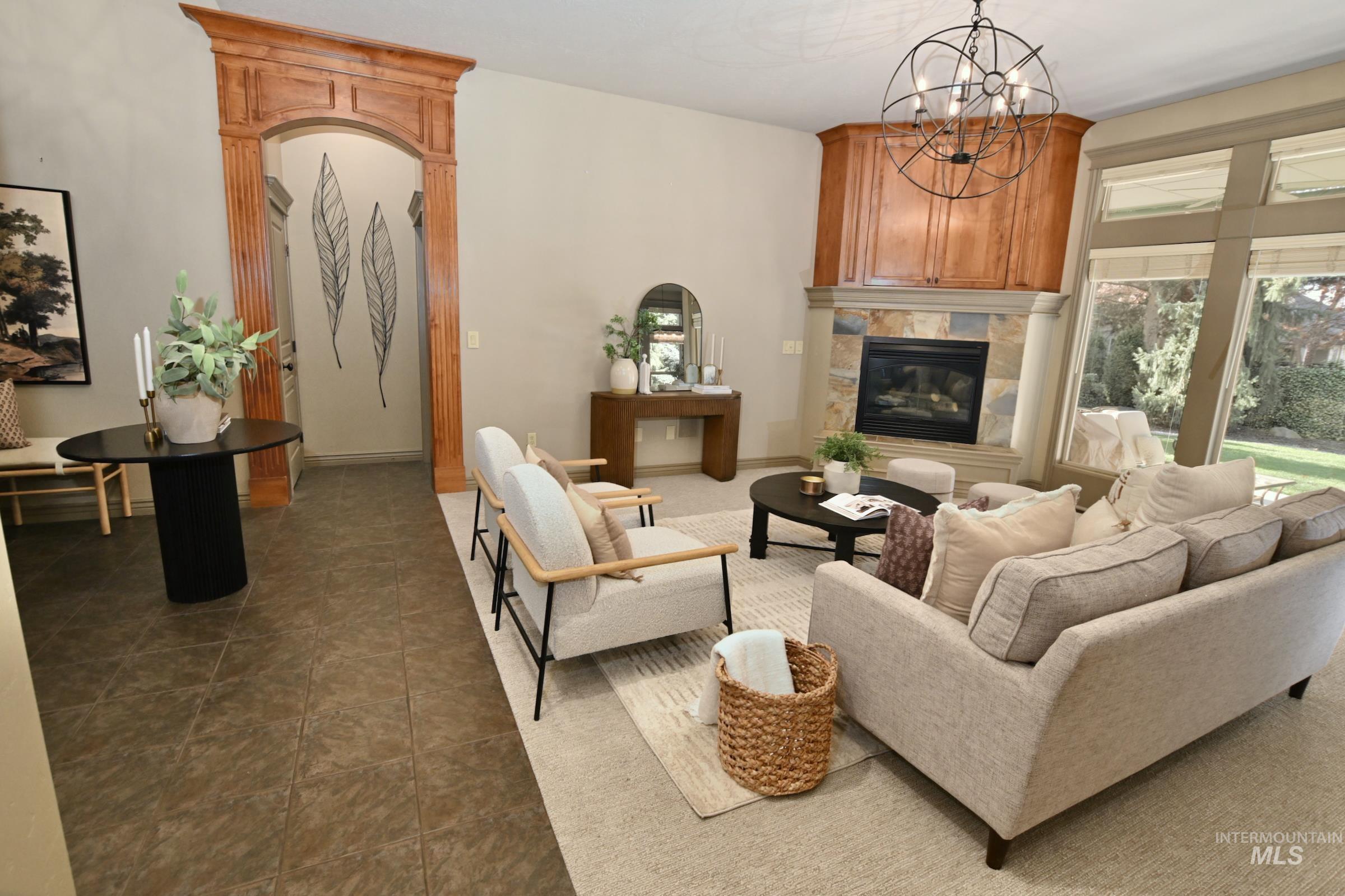 Living room featuring a tile fireplace, a chandelier, and dark tile patterned floors