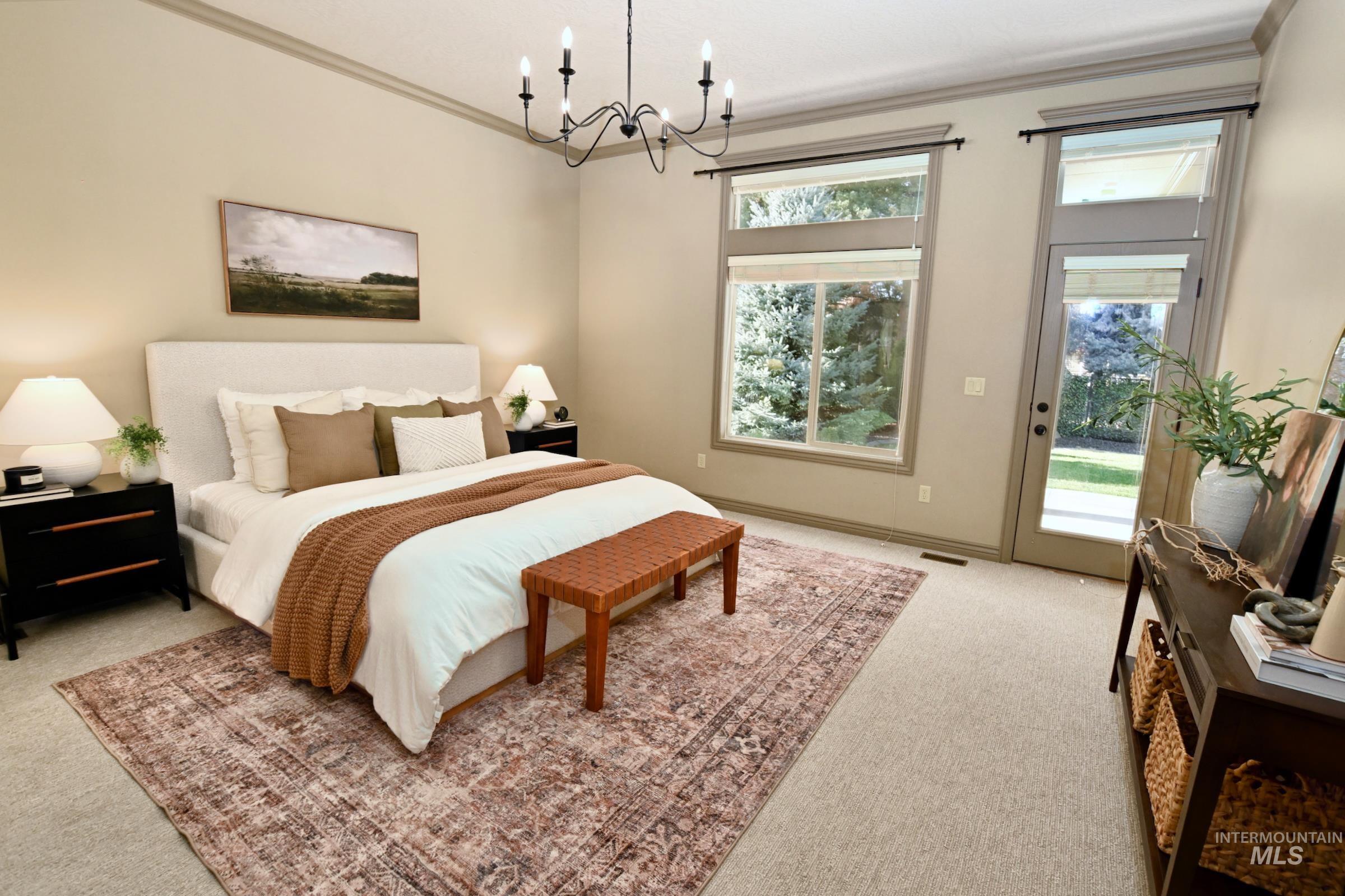Bedroom with ornamental molding, access to exterior, light carpet, and a chandelier
