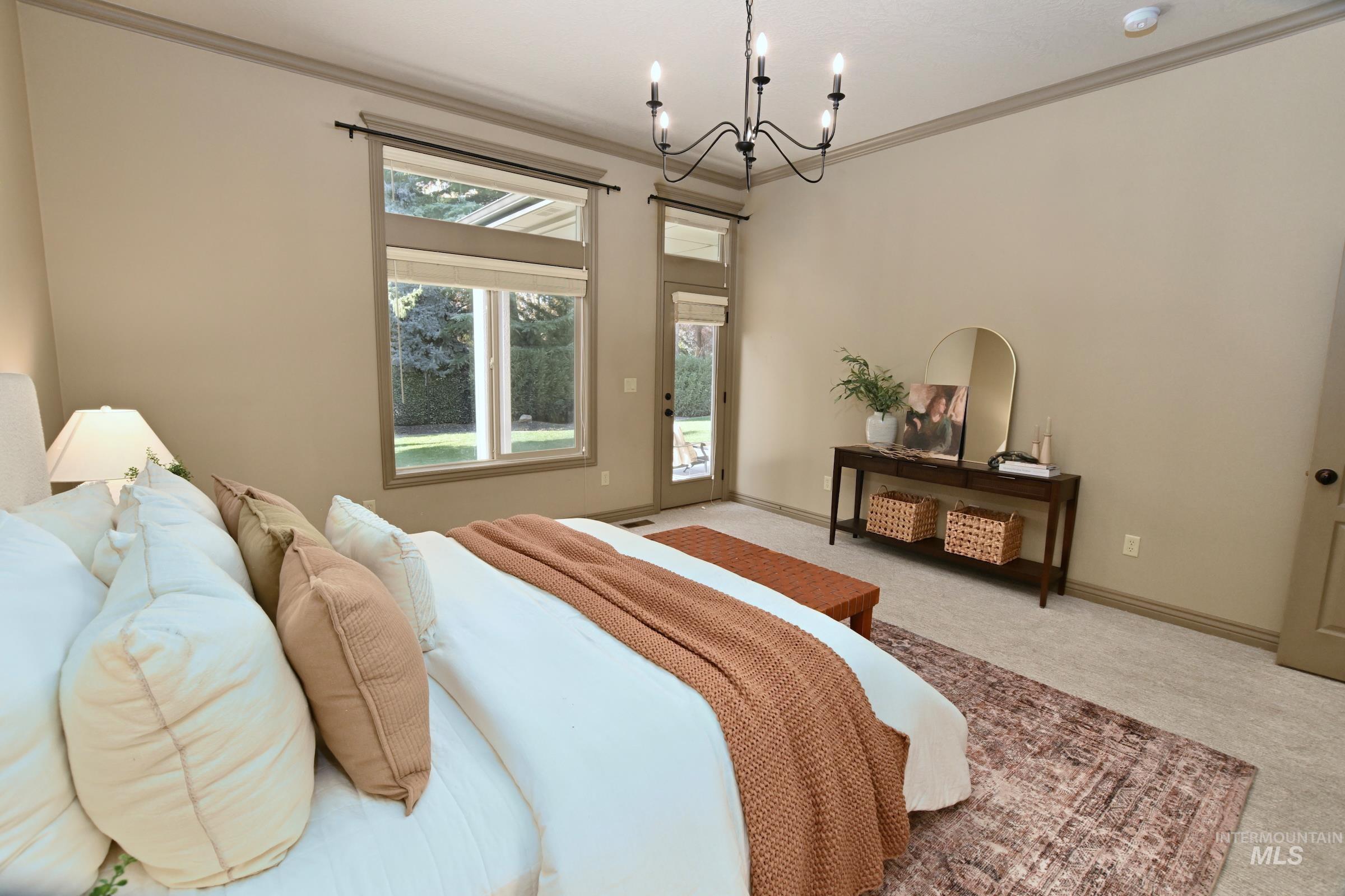 Carpeted bedroom with ornamental molding, access to outside, and a chandelier